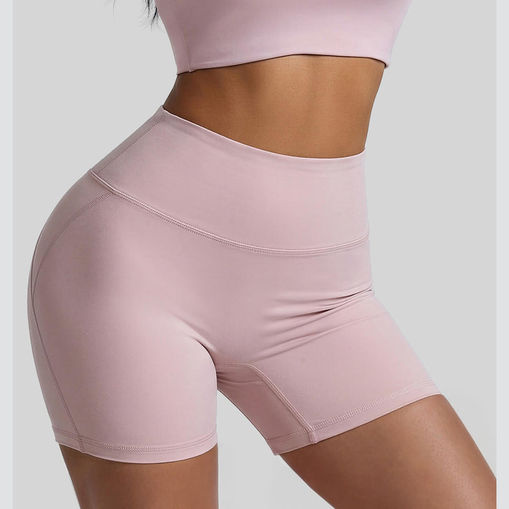 Front and side view of pink athletic biker shorts showing the high-rise tummy control waistband and slimming fit
