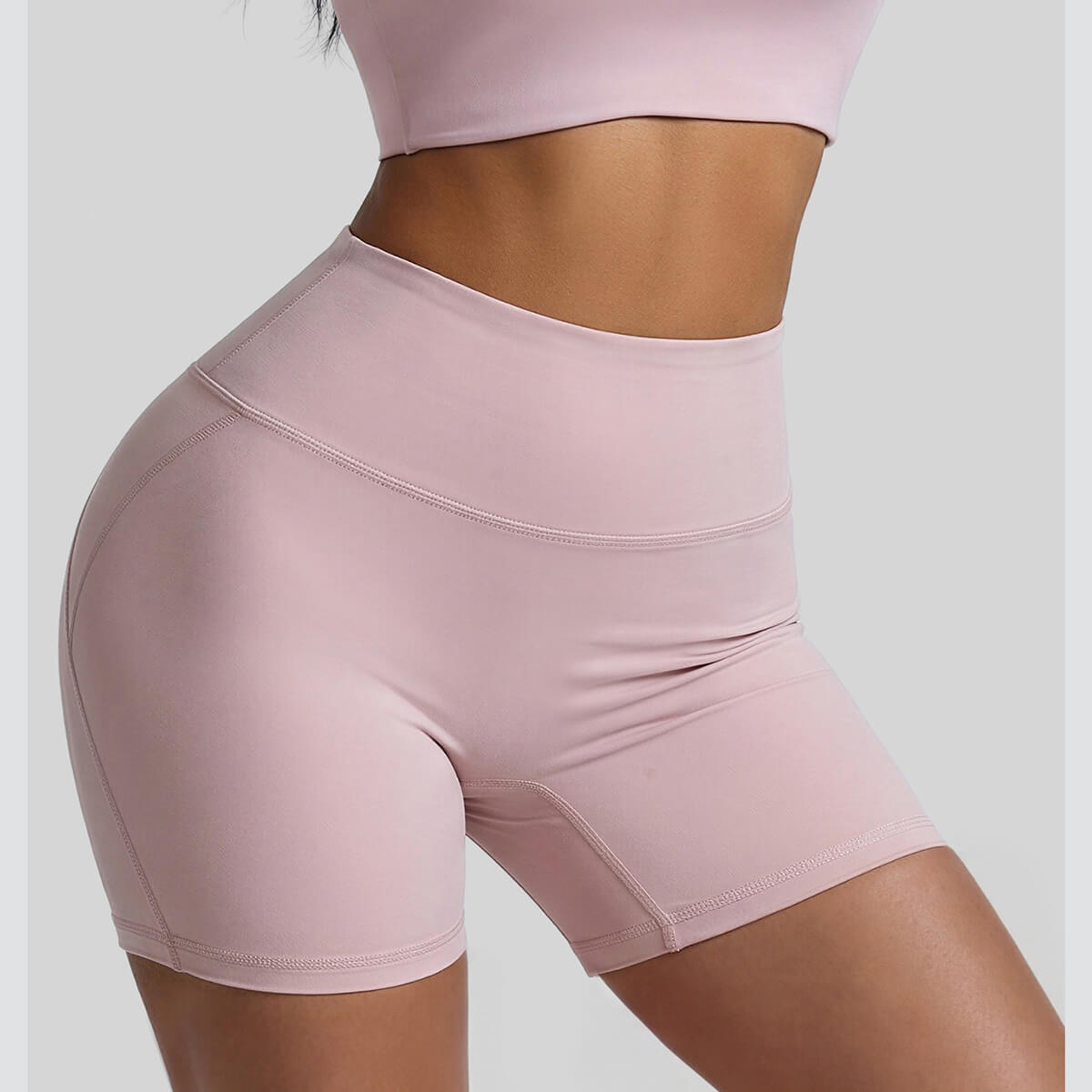 Front and side view of pink athletic biker shorts showing the high-rise tummy control waistband and slimming fit
