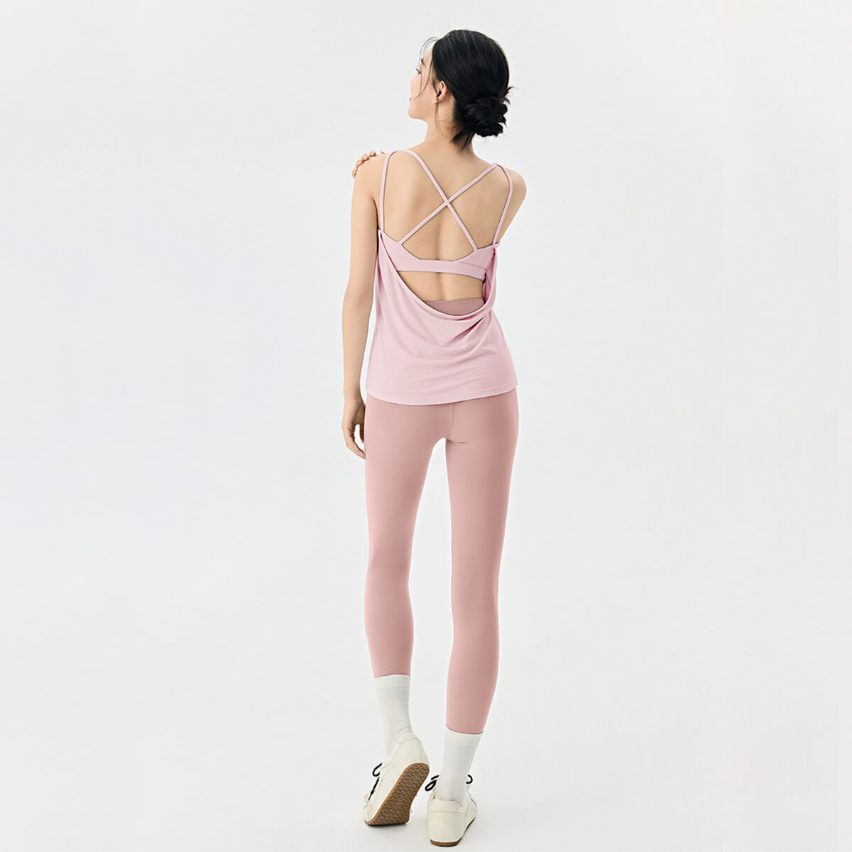 Full back view of a pink moisture-wicking yoga set with high-waisted leggings and an open back tank top.