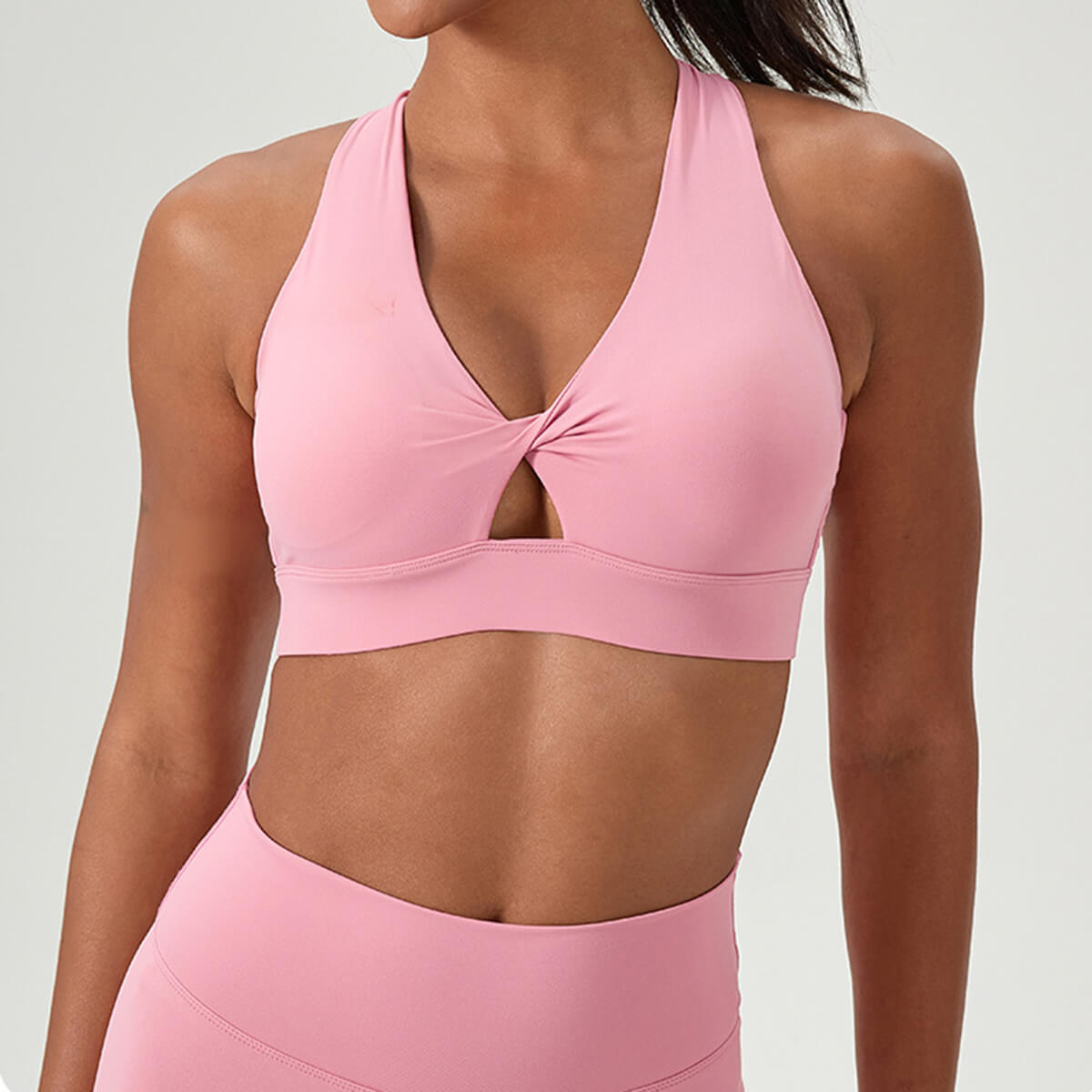 Pink v-neck sports bra with a stylish front twist and keyhole cutout detail.