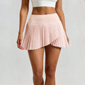 Front view of a light pink pleated tennis skirt featuring an asymmetrical hem and high-waisted design for women's athletic wear.