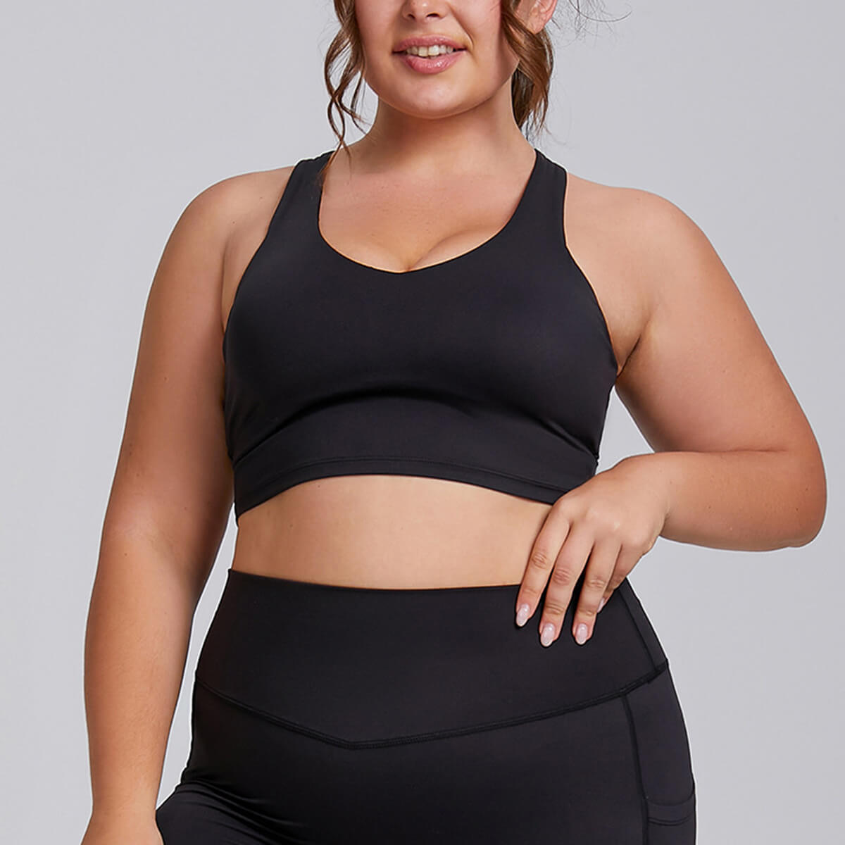 Curvy model wearing a high-impact black sports bra front view.