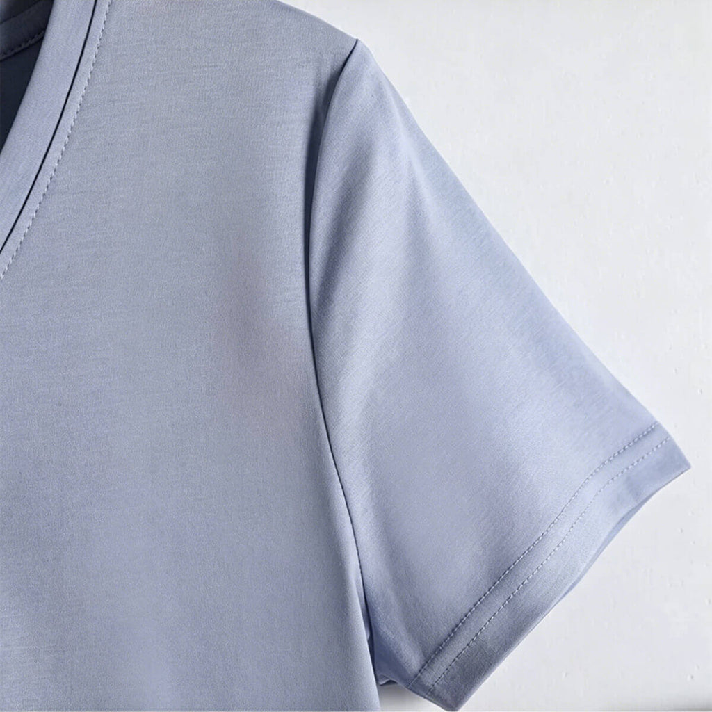 Macro shot of the V-neckline construction and the silky-smooth fabric texture of a high-thread-count 80S cotton T-shirt.