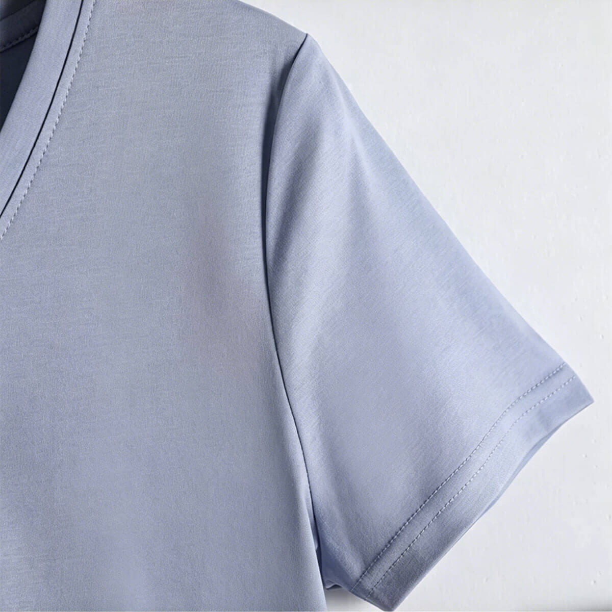 Macro shot of the V-neckline construction and the silky-smooth fabric texture of a high-thread-count 80S cotton T-shirt.