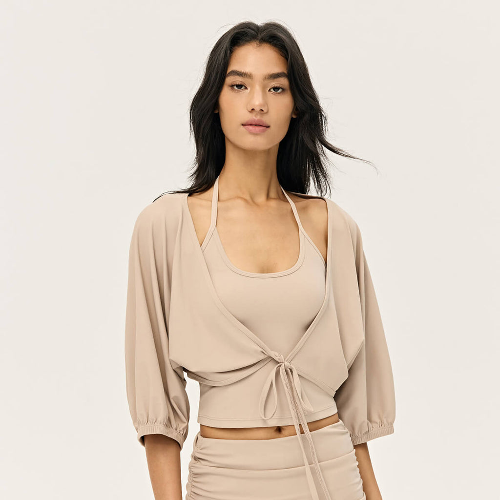 Front view of a sand-beige ballet-style cropped shrug featuring puffy balloon sleeves and a front tie closure.