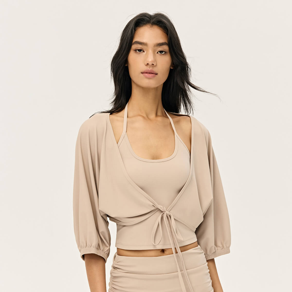 Front view of a sand-beige ballet-style cropped shrug featuring puffy balloon sleeves and a front tie closure.