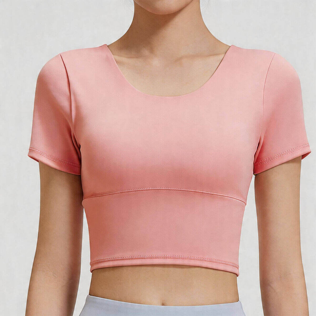 Front close-up of a scoop neck women's workout crop top in peach pink, featuring high-stretch fabric and a supportive wide band.