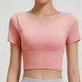 Front close-up of a scoop neck women's workout crop top in peach pink, featuring high-stretch fabric and a supportive wide band.