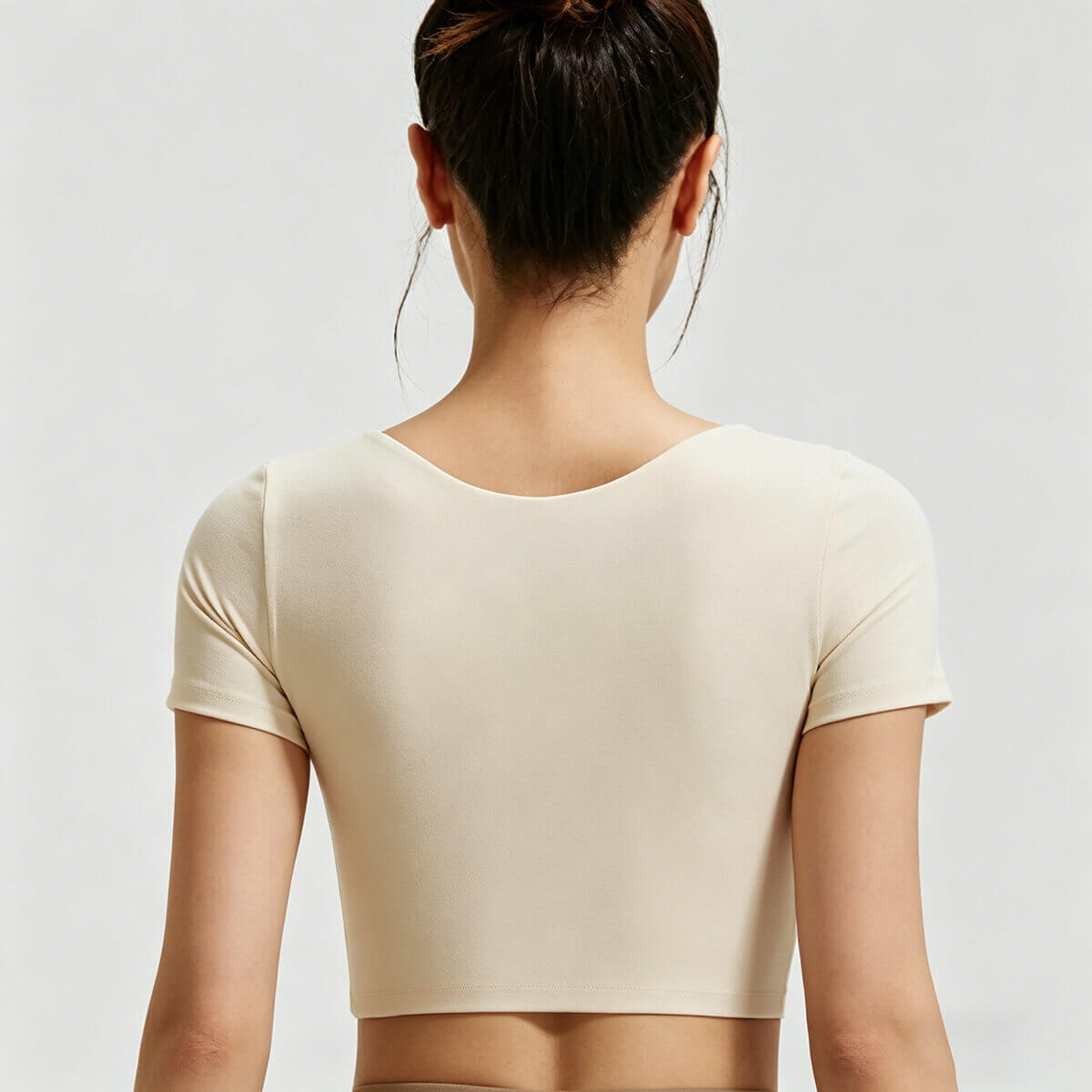 Full back view of a high-stretch cream-colored sports crop top, highlighting the smooth seamless finish and comfortable athletic fit.