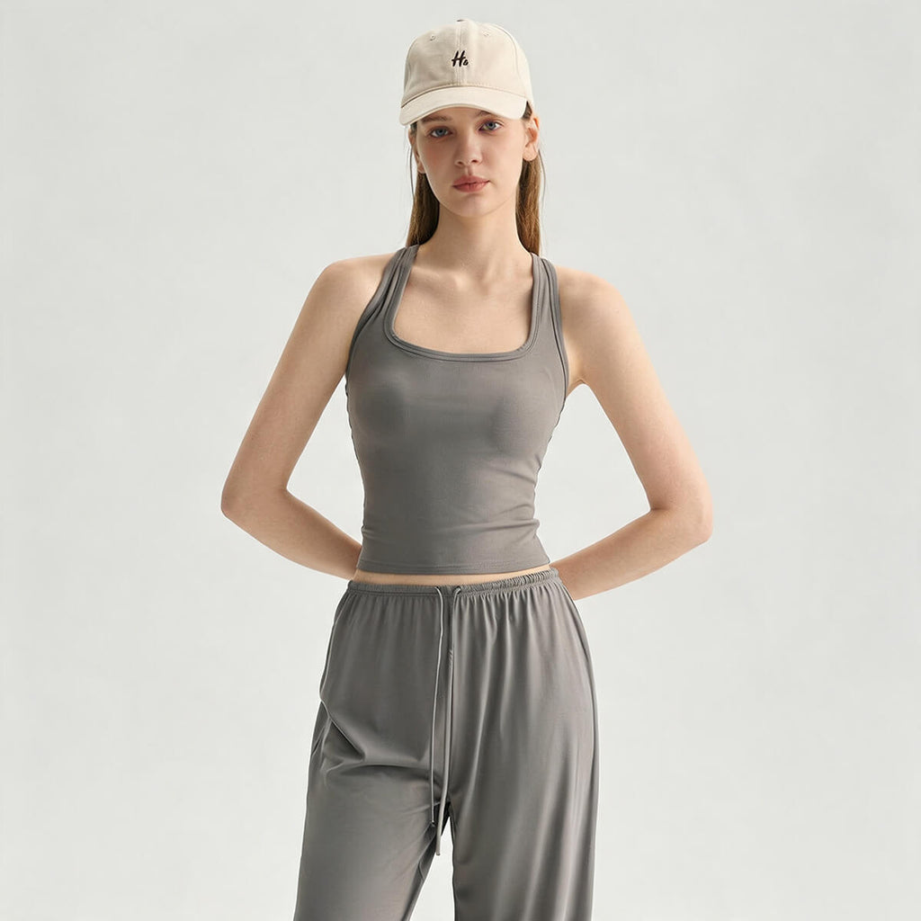 A woman posing in a slate gray athletic camisole featuring a flattering square neckline.