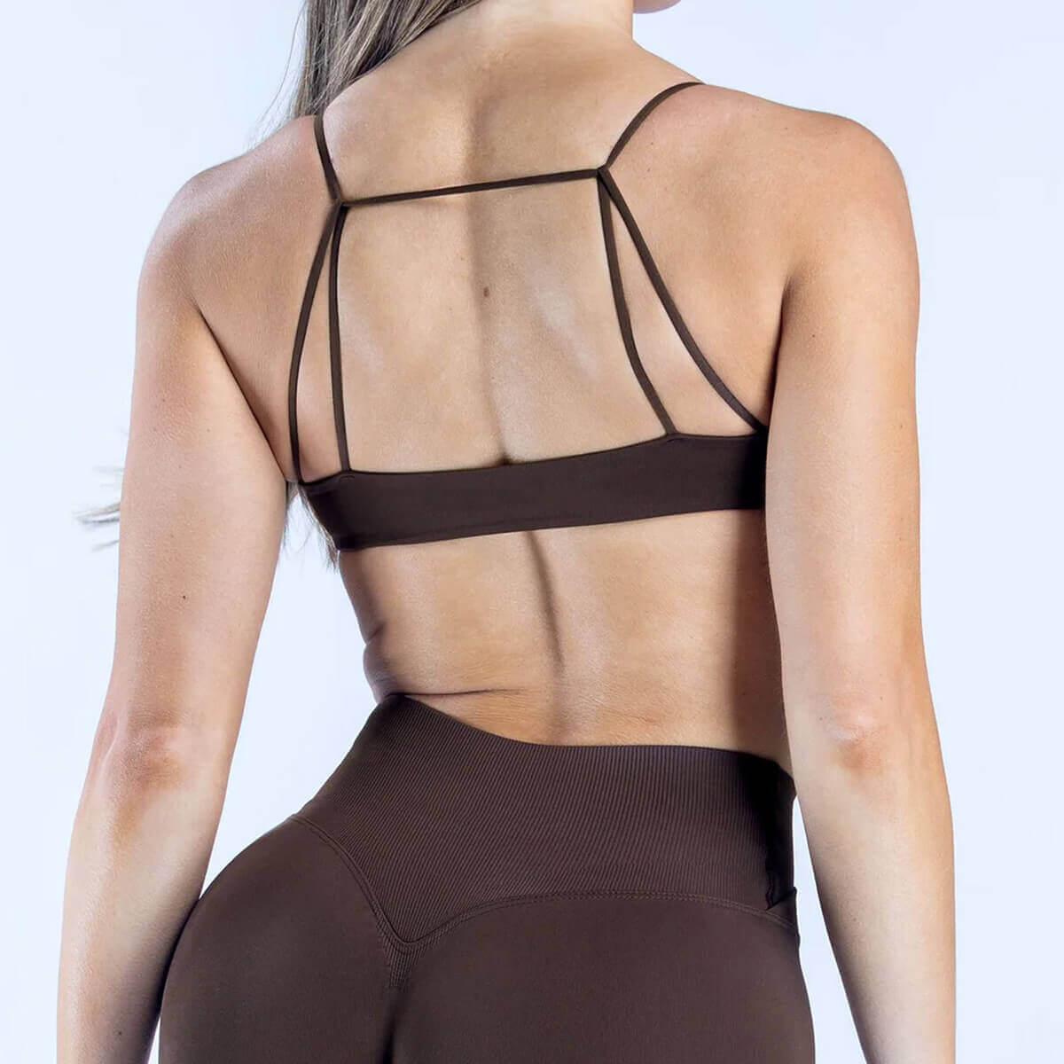Back view of an espresso brown sports bra highlighting the minimalist multi-strap open back design.