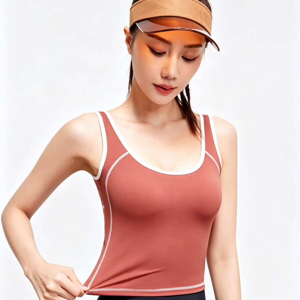 Close-up of a terracotta athletic tank top for women showing the high-stretch performance fabric and white contrast stitching details