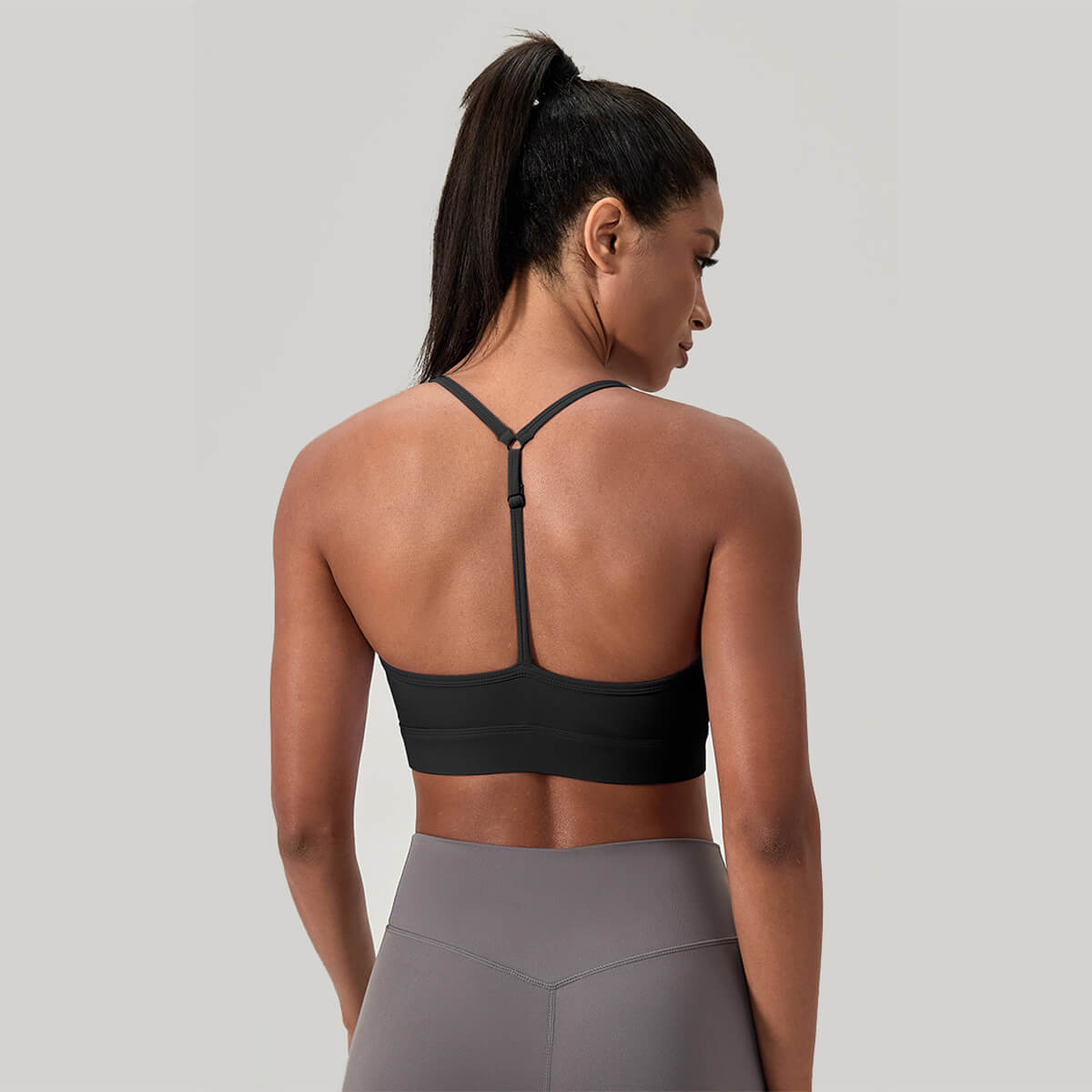 Back view of a black sports bra featuring a minimalist thin Y-back strap design to allow for a full range of motion during workouts.