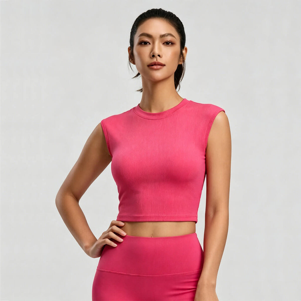 A woman posing in a raspberry pink high-neck crop top, featuring a retro-inspired sleeveless design and slim fit, perfect for a 90s vintage activewear look.