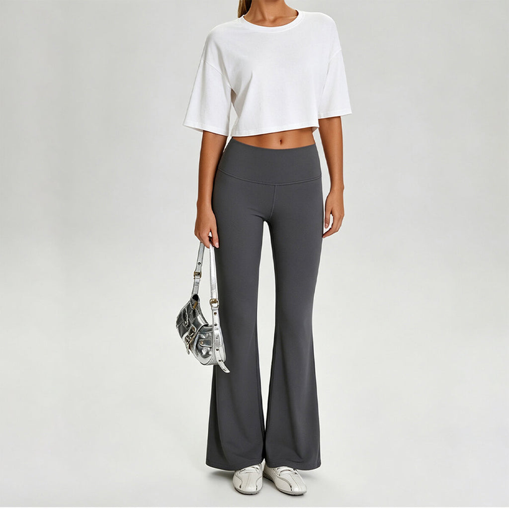 A woman styling a white boxy crop top with charcoal gray leggings and sneakers for a trendy streetwear vibe.
