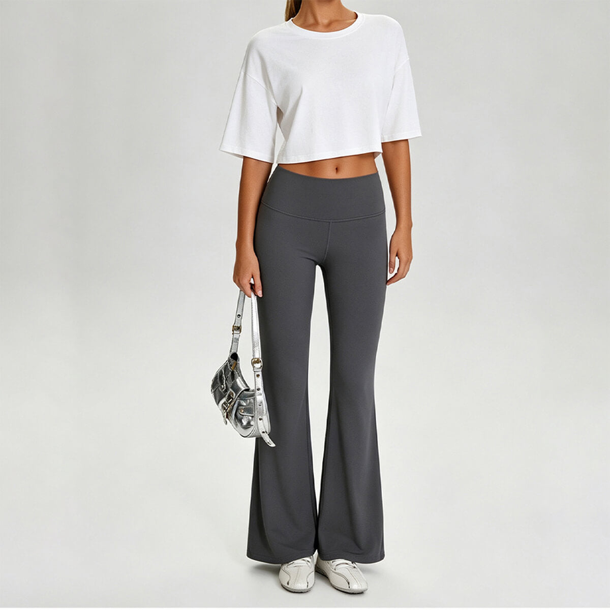 A woman styling a white boxy crop top with charcoal gray leggings and sneakers for a trendy streetwear vibe.