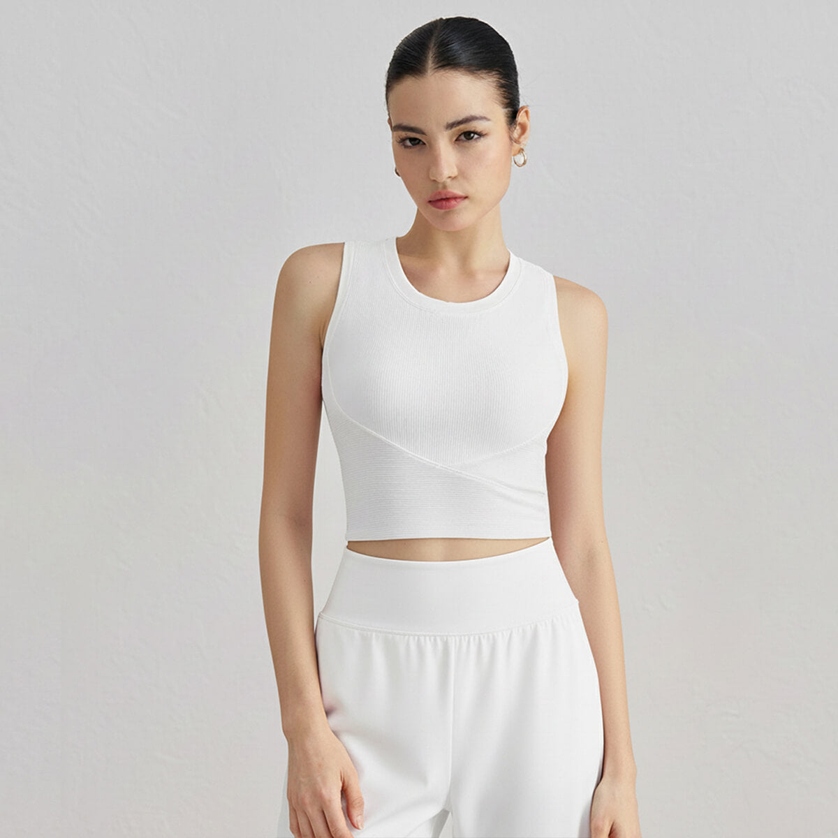 Front view of a woman wearing a crisp white ribbed high-neck cropped tank top for a clean athletic look.