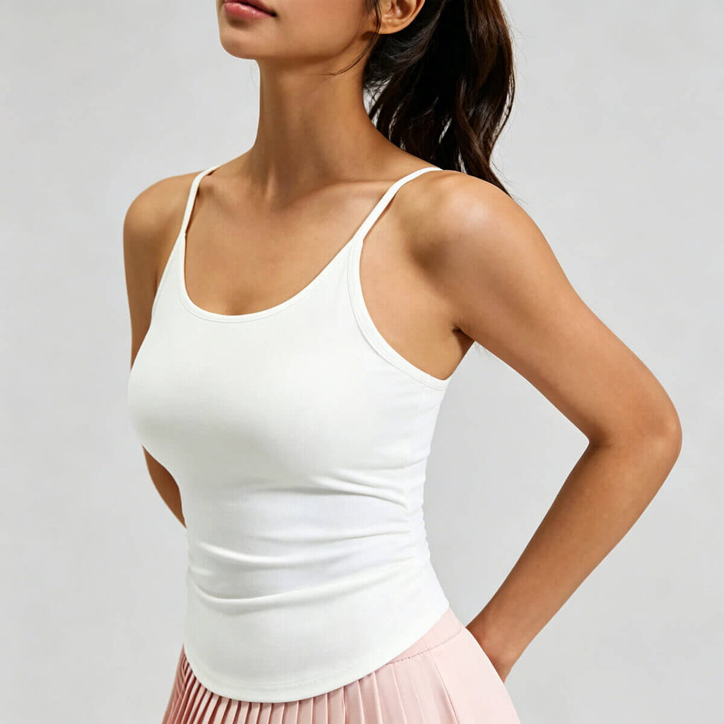 A woman modeling a crisp white yoga camisole with built-in padding and a flattering curved hem, perfect for fitness and casual wear
