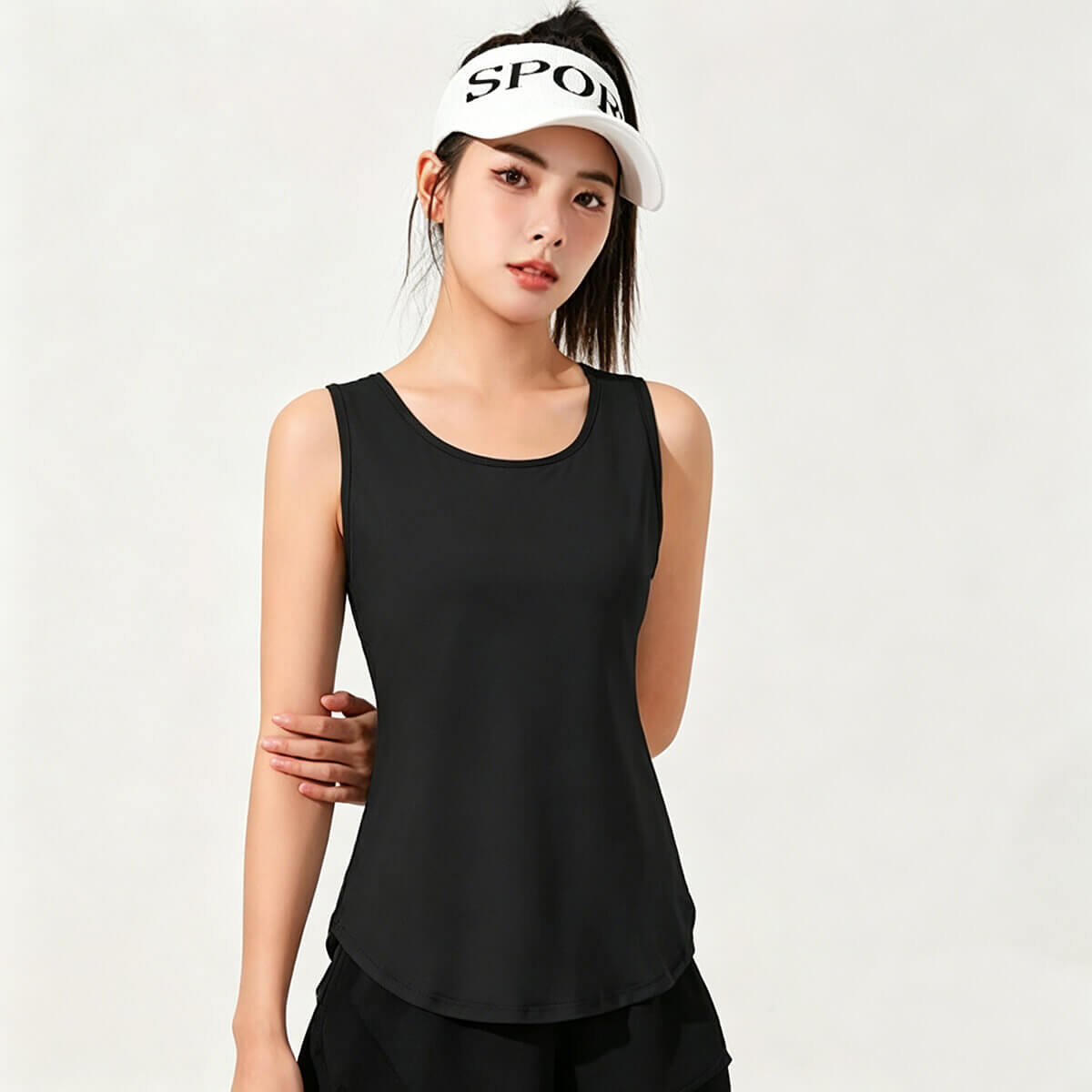 A woman modeling a classic black gym tank top paired with a sports visor for a trendy athleisure look.