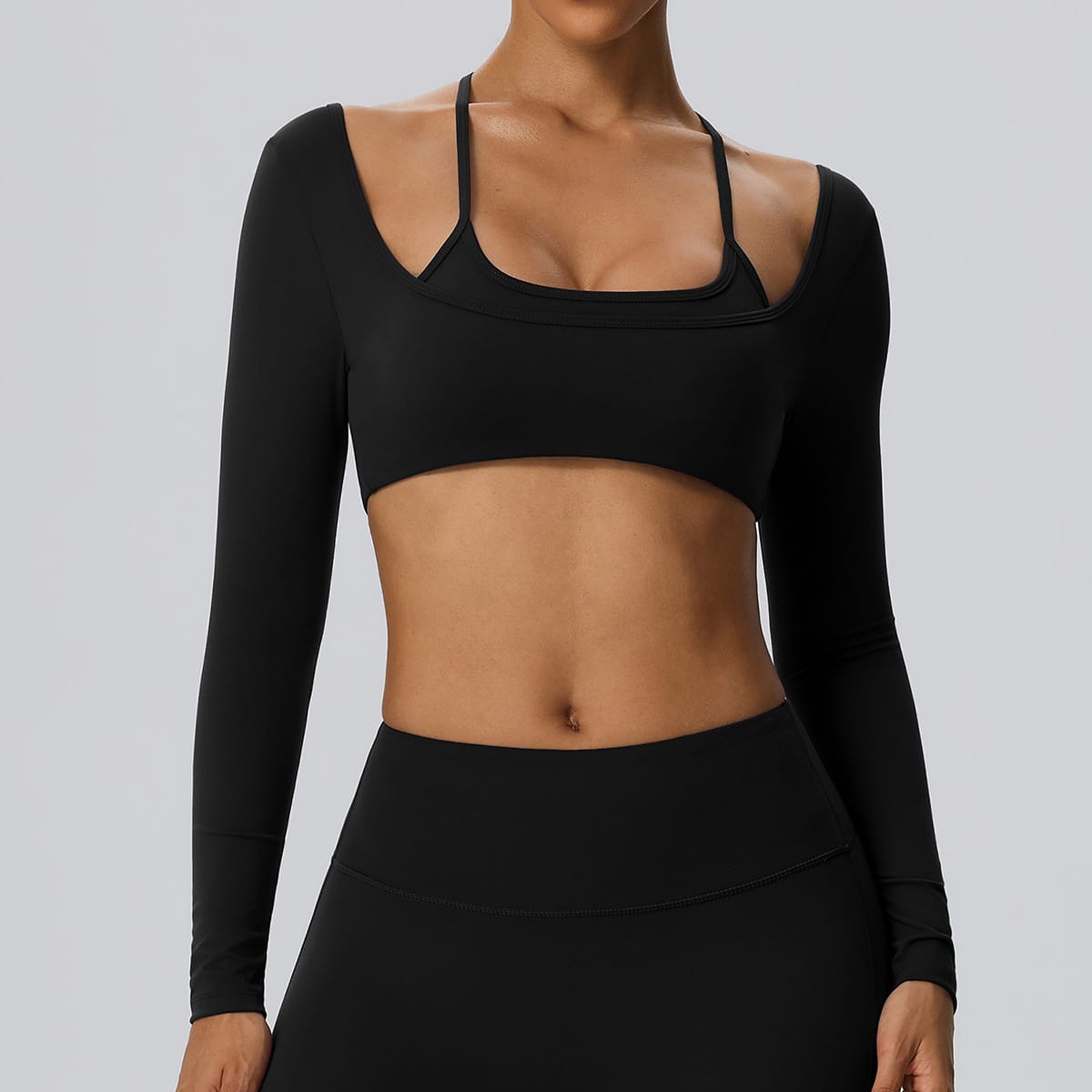  Front view of a black 2-in-1 long sleeve shrug sports bra.
