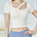 Front view of a women's ivory yoga crop top featuring a stylish asymmetric cutout neckline and slim-fit short sleeves.