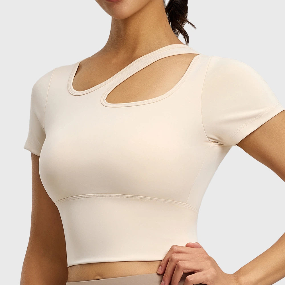 Women's asymmetrical cutout short sleeve yoga crop top with built-in pads in cream with custom logo, OEM activewear manufacturer - front view.