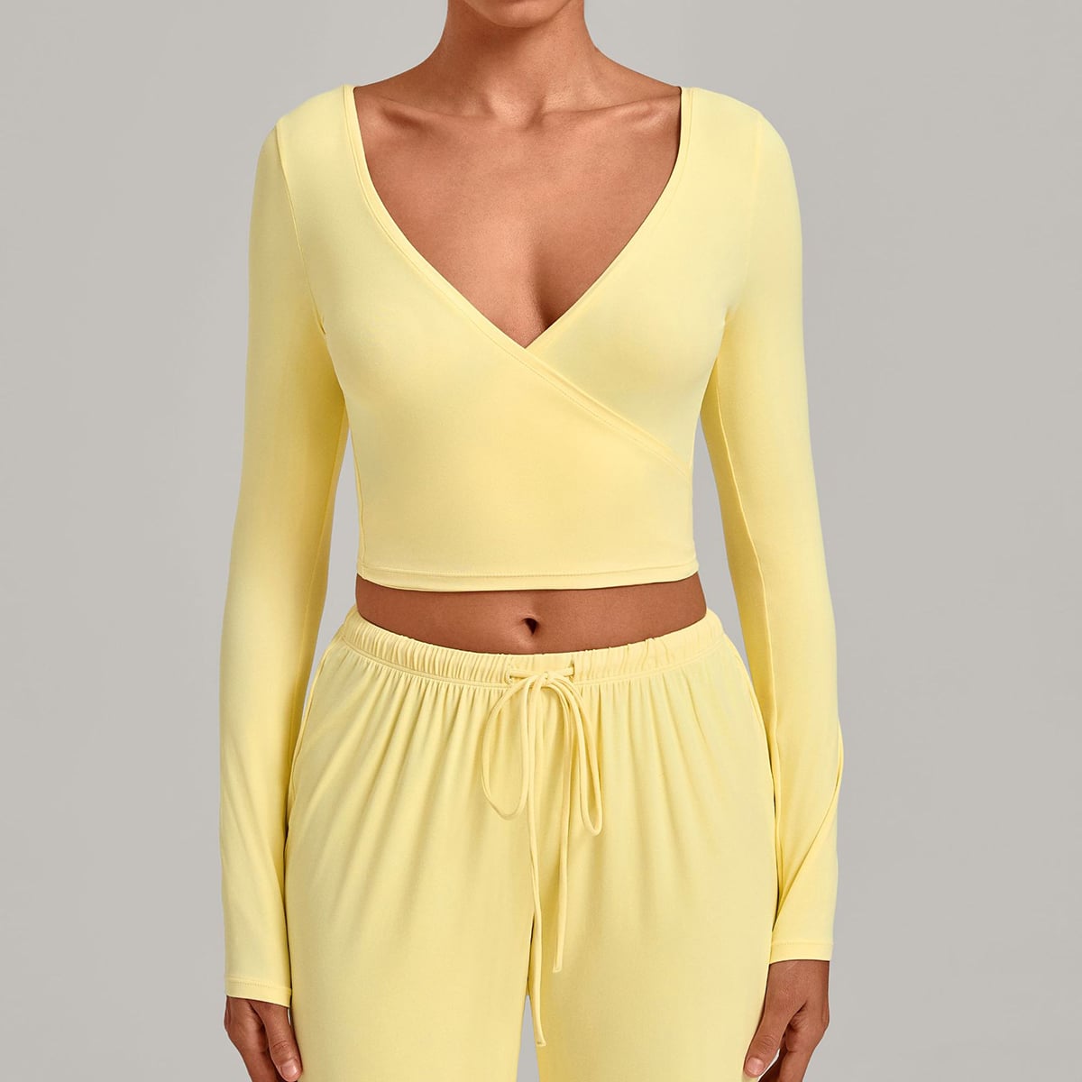 Woman wearing a pale butter yellow long-sleeve ballet wrap top.