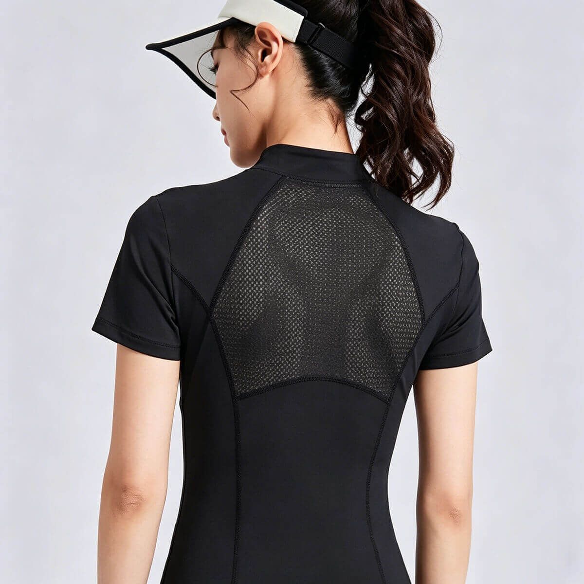 Back view of a women's black half-zip athletic top featuring a large breathable mesh panel for maximum ventilation during tennis, golf, or gym workouts.