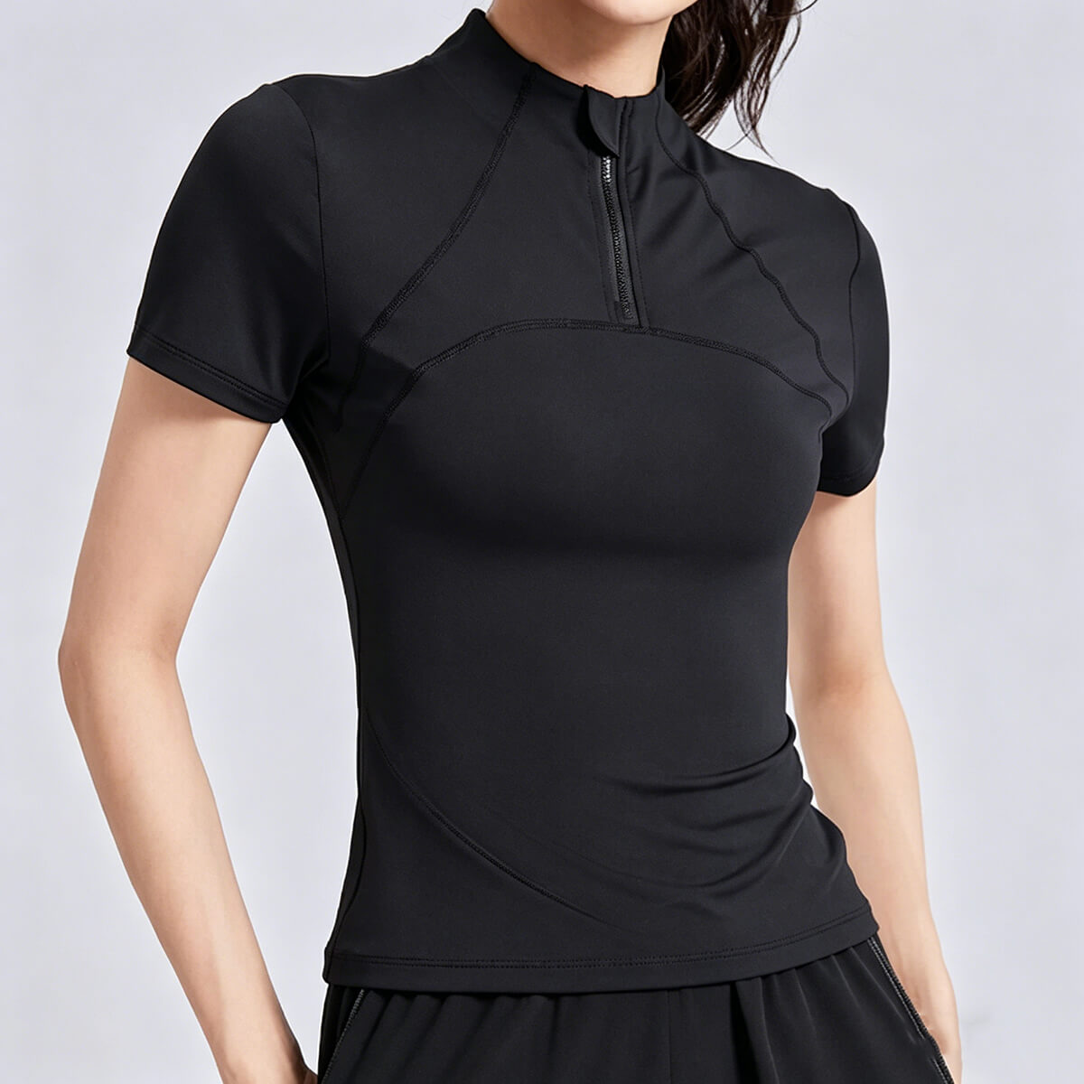 Women's black half-zip workout top with a slim-fit design and contouring seams for a flattering athletic look