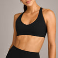 A woman wearing a high-impact black racerback sports bra with a scoop neckline, perfect for gym workouts and yoga.