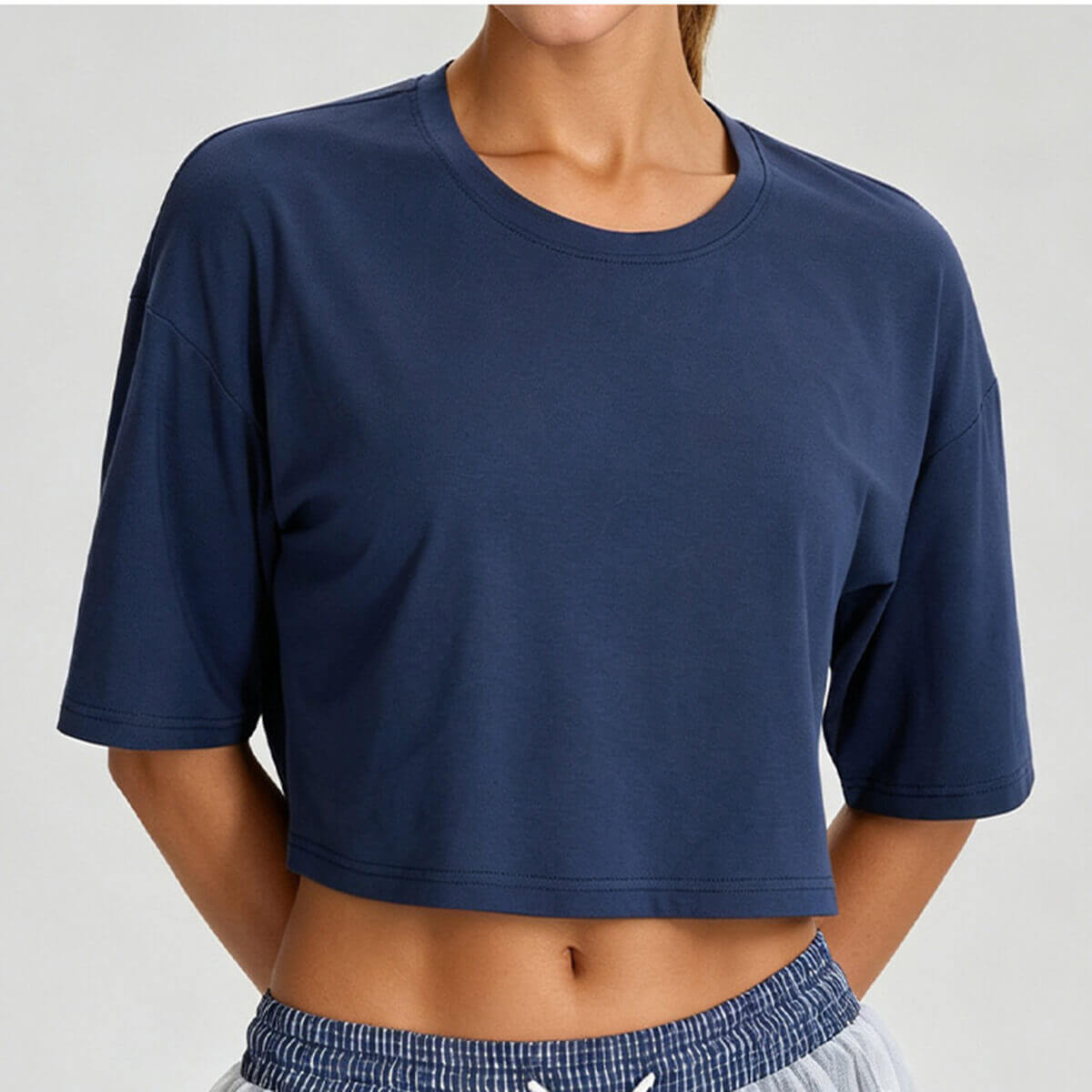 Front view of a women's boxy cropped workout tee in navy blue, featuring a relaxed oversized fit and crew neckline.