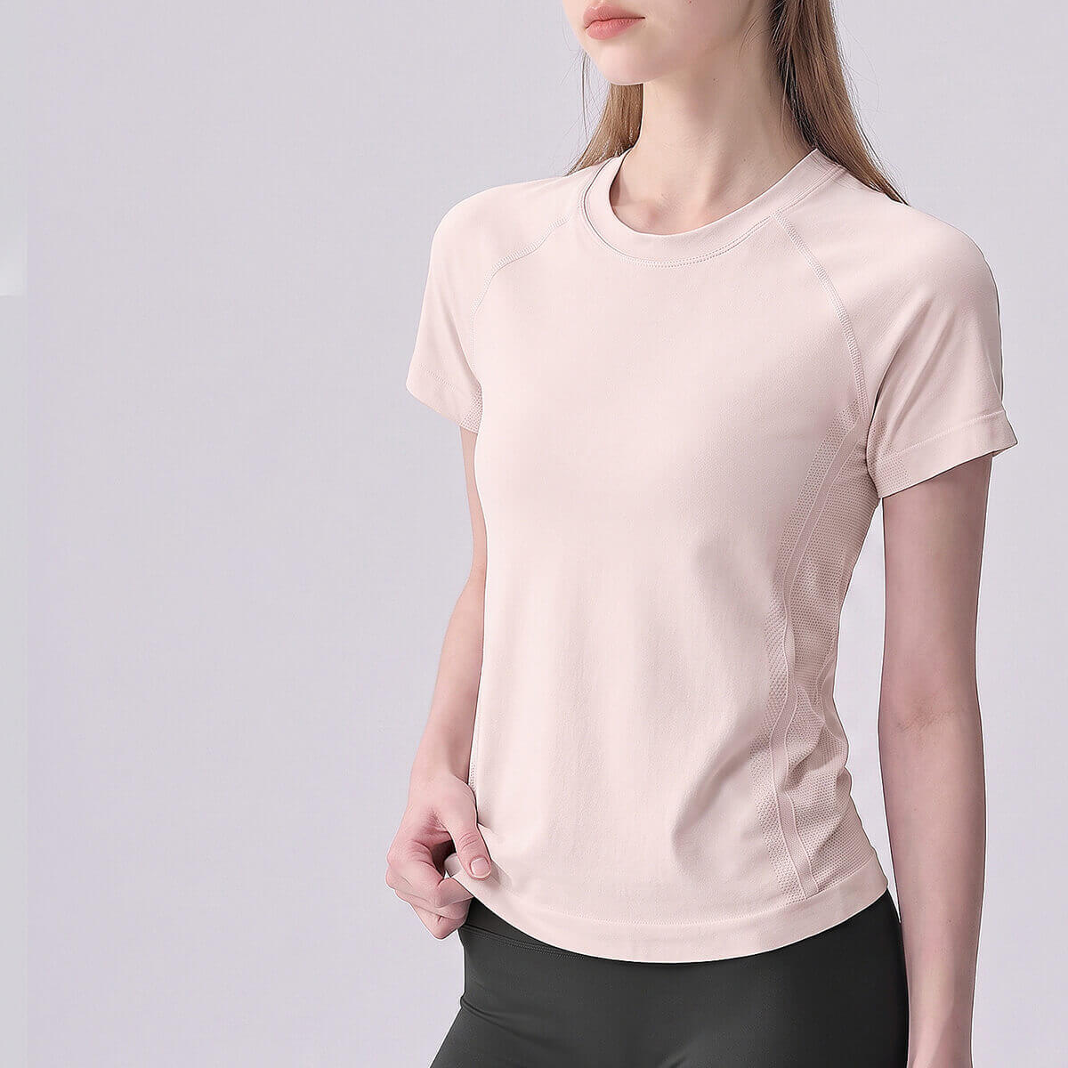 Woman wearing a light pink moisture-wicking athletic gym t-shirt.