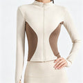 Front view of a women's color-block full-zip athletic jacket in beige and brown, featuring a slim fit and stand collar.
