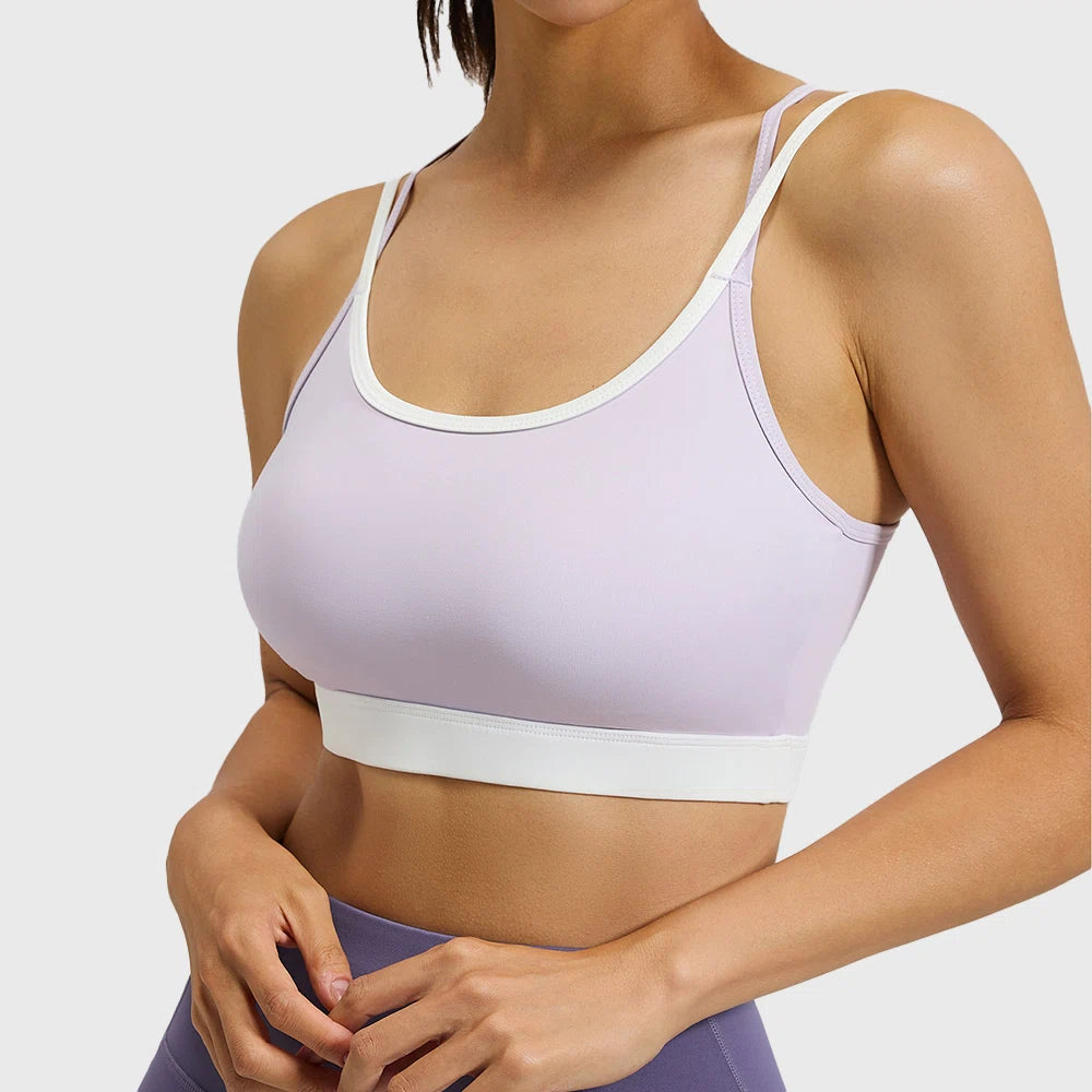 Front view of women's lilac purple colorblock sports bra with contrast white trim and custom logo, produced by activewear manufacturer.