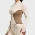 Side profile showing thumbholes on women's contour athletic jacket in cream and brown with custom logo, private label manufacturer.