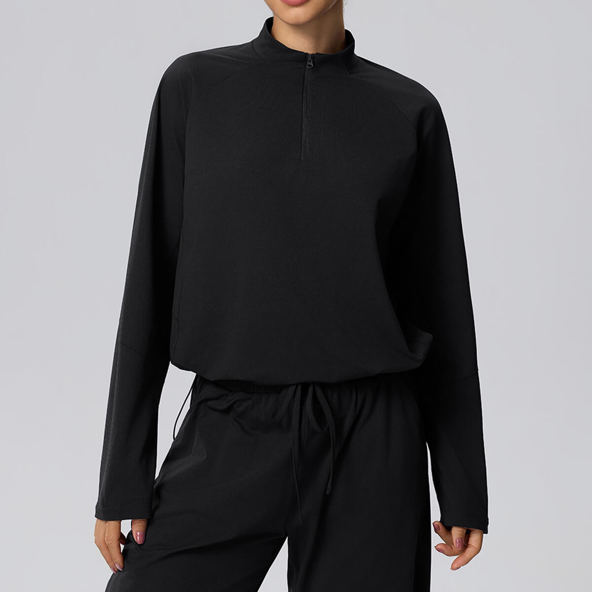 Front view of a black women's cropped half-zip athletic pullover with a mock neck and textured fabric.