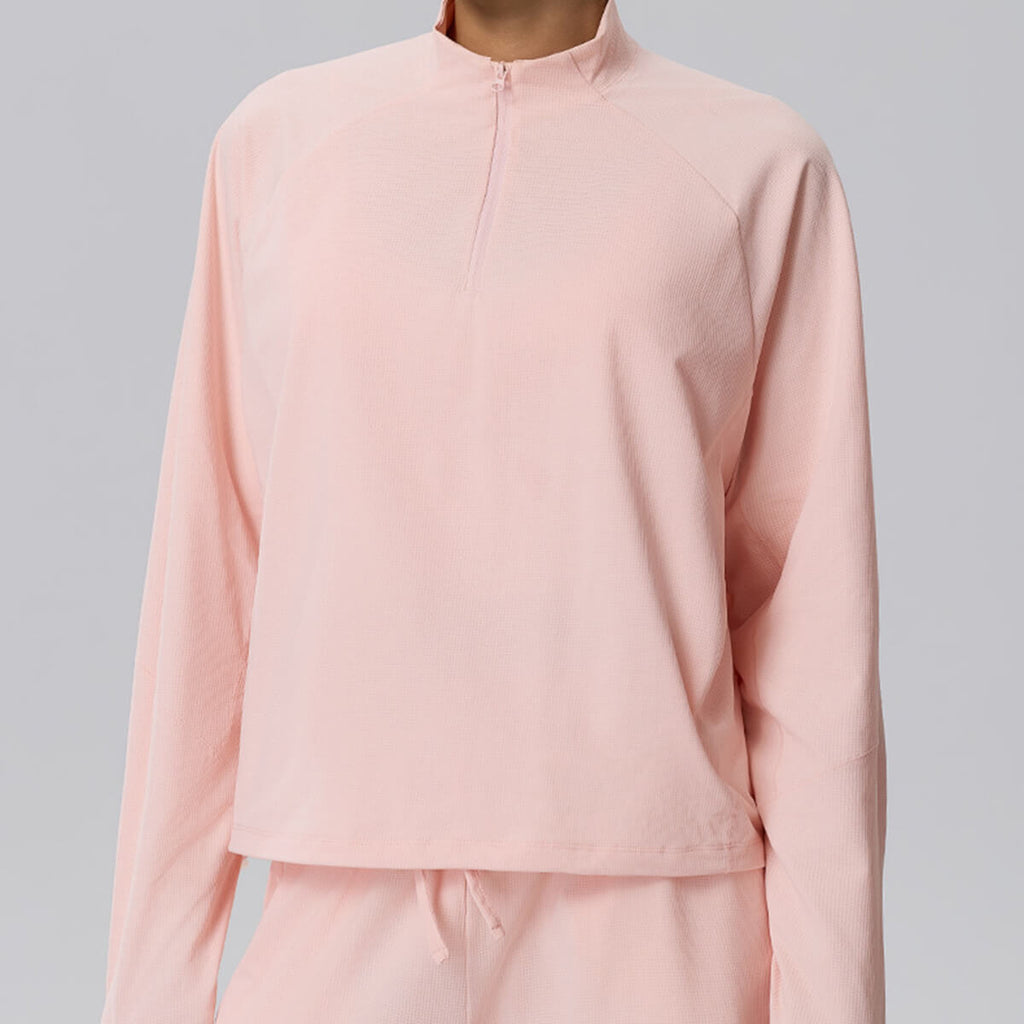Front view of a blush pink cropped sweatshirt with a quarter-zip collar and a modern athletic silhouette.