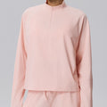 Front view of a blush pink cropped sweatshirt with a quarter-zip collar and a modern athletic silhouette.