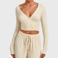 Women's deep V-neck long sleeve wrap crop top in cream with custom logo, OEM activewear manufacturer - front view.