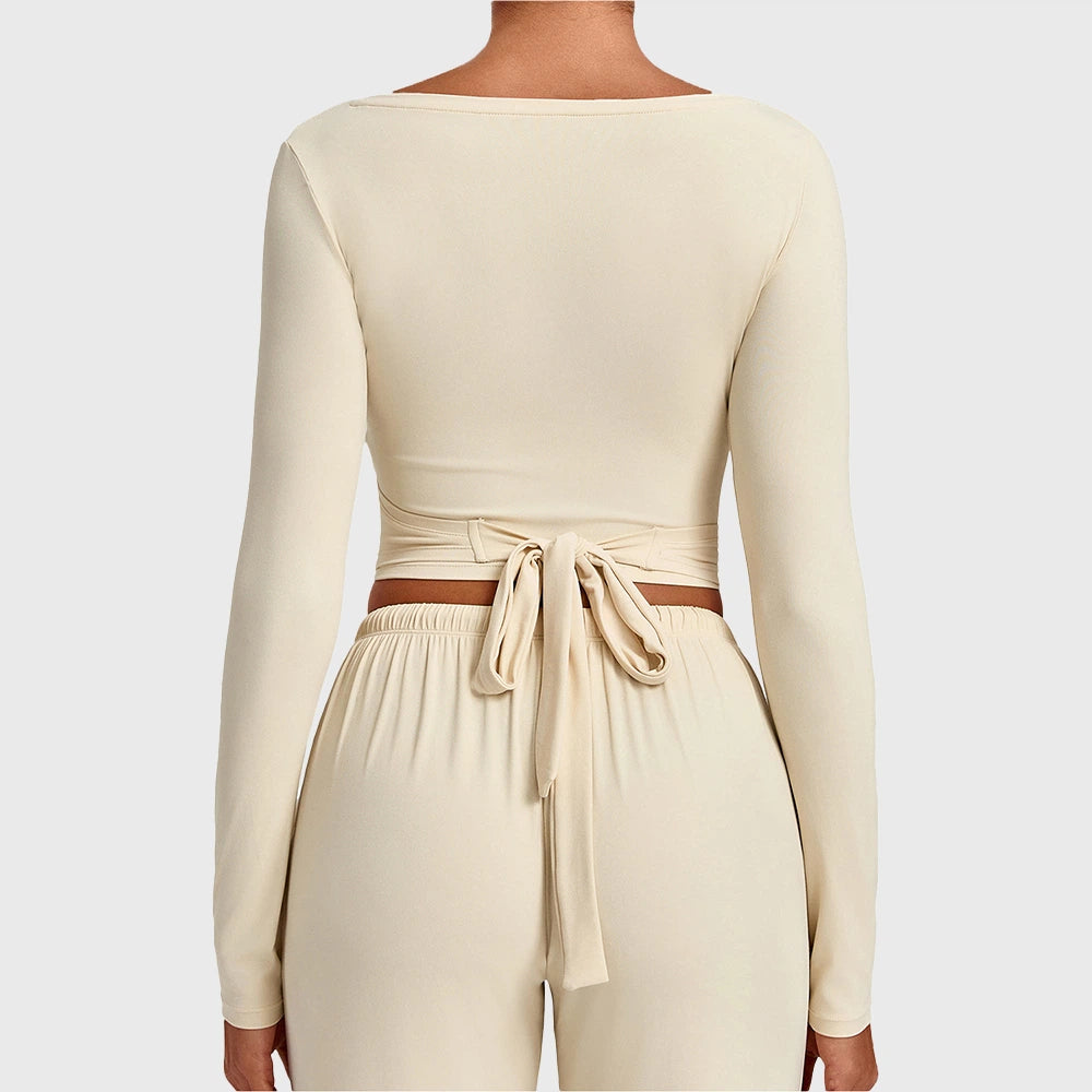 Back view showing bow tie-back detail on women's cream long sleeve crop top with custom logo, clothing manufacturer.