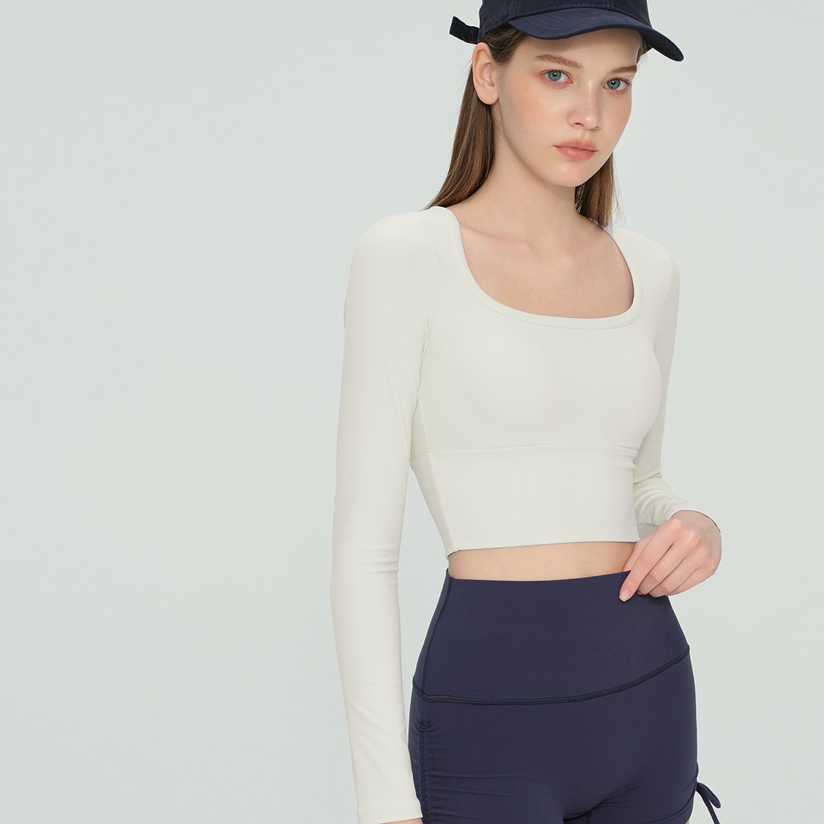 Model wearing an ivory cream square neck athletic long-sleeve top.