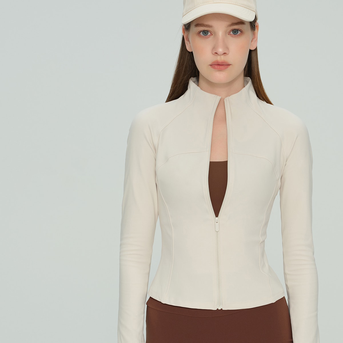 Front view of a cream white lightweight workout jacket with contour seams.