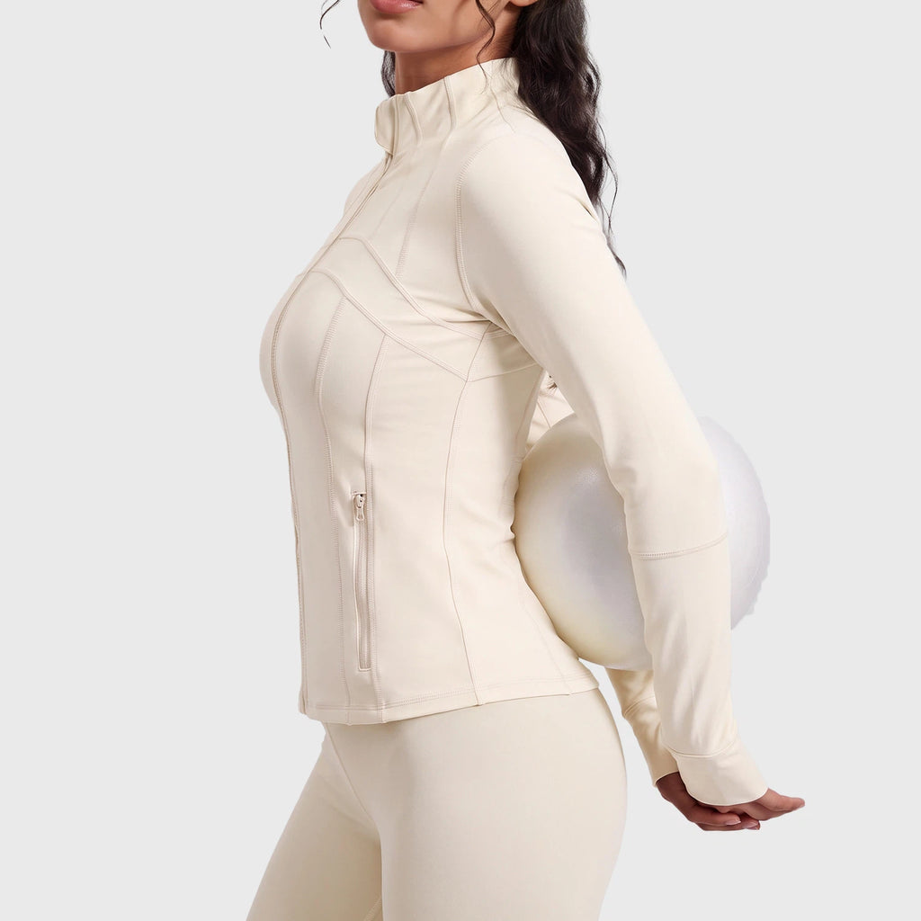 Side profile of women's stand collar athletic jacket with zipper pockets and thumbholes in cream with custom logo, direct clothing manufacturer.
