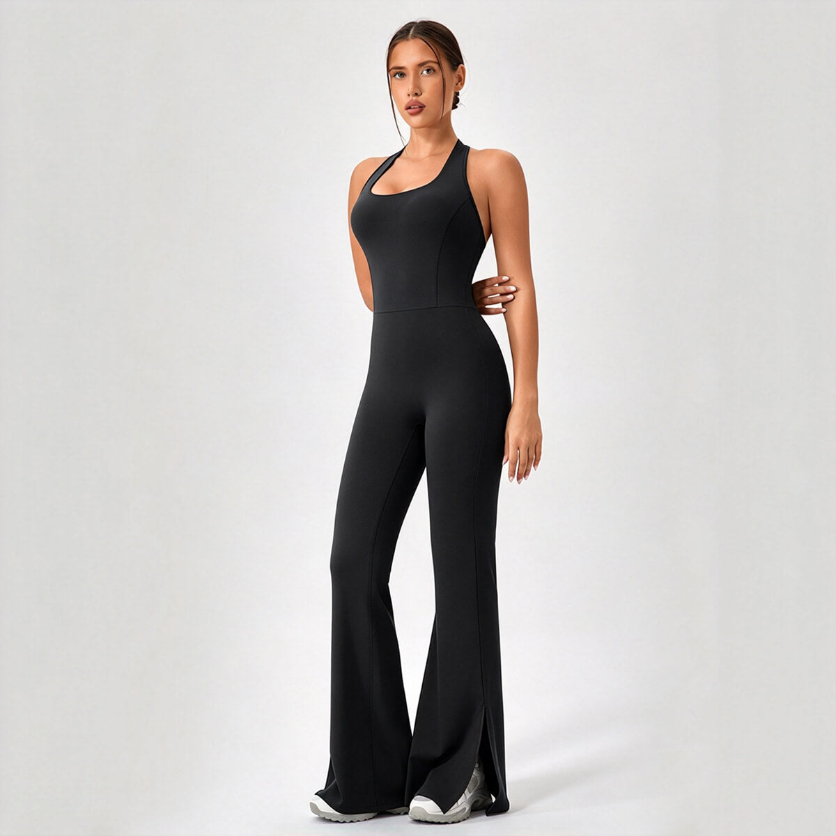 Three-quarter view of a black backless flare leg workout catsuit with split hems.