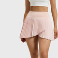 Women's high waist asymmetrical pleated tennis skirt in blush pink with custom logo, OEM fitness apparel manufacturer - front view.