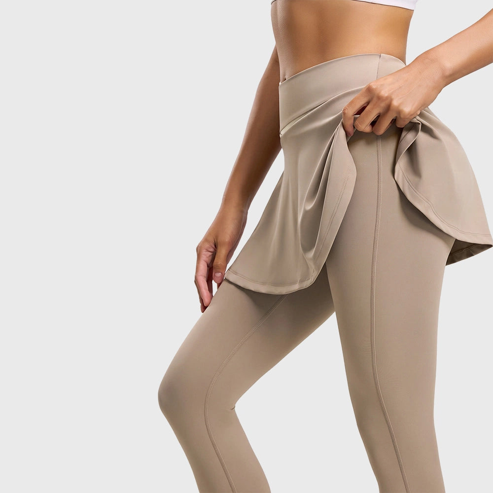 Close-up view lifting skirt overlay on women's tan 2-in-1 yoga leggings with custom logo, OEM gym wear manufacturer.

