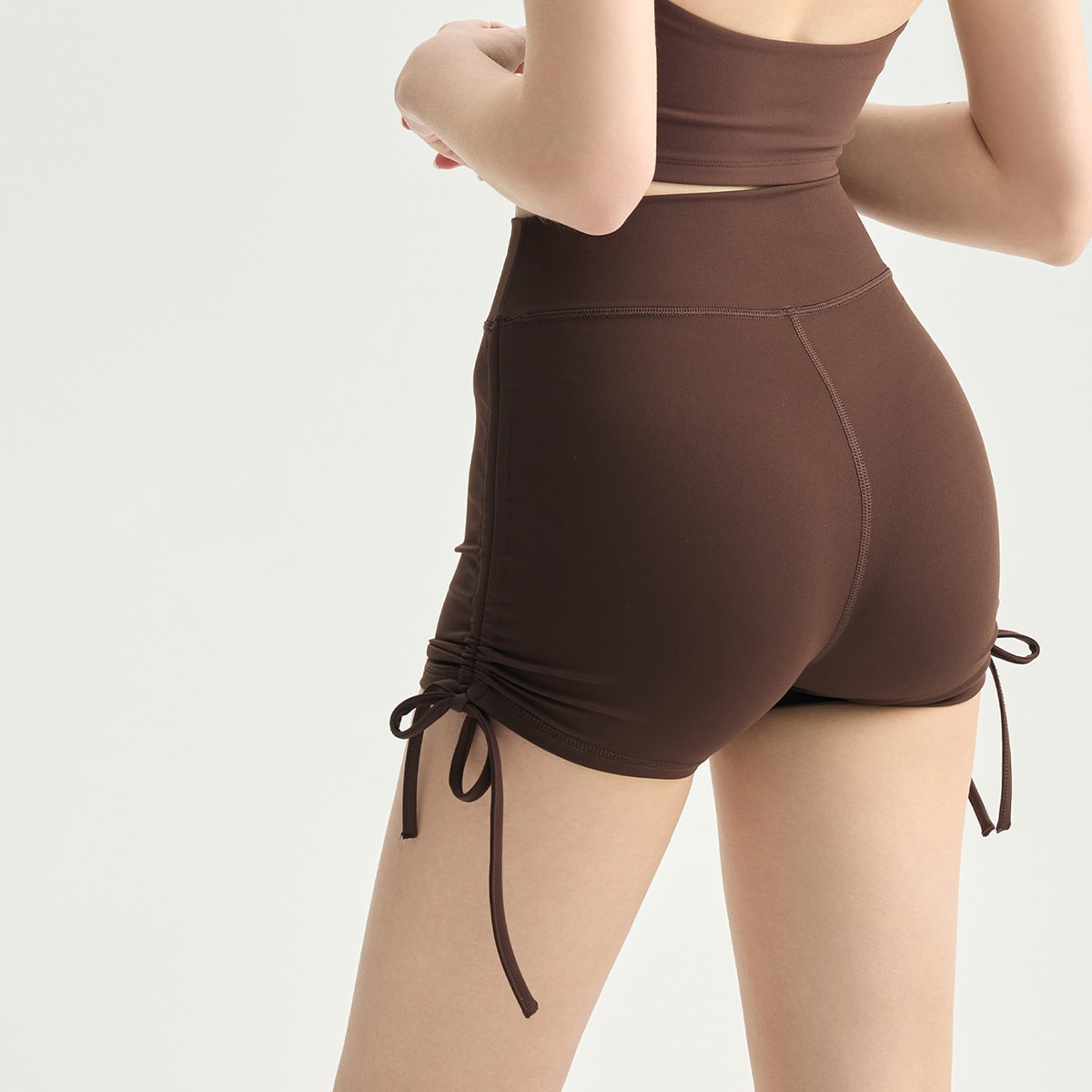 Rear view of chocolate brown ruched side-drawstring athletic shorts.