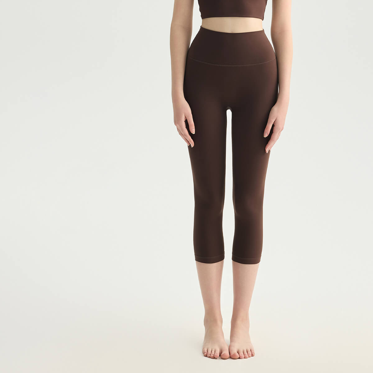 Front view of dark brown high-waisted capri yoga pants with a supportive tummy-control waistband.