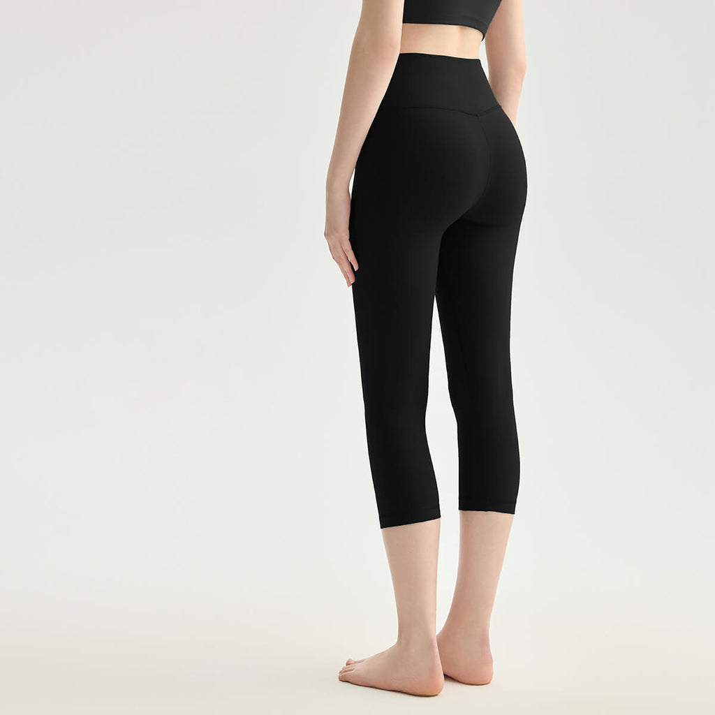 Rear view of a woman wearing black high-waisted crop yoga pants with a body-hugging fit.