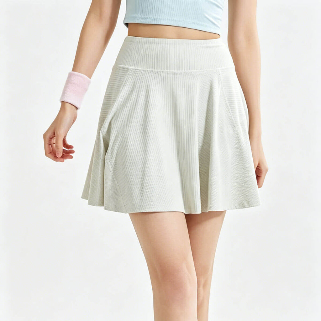 Front view of high-waisted ribbed tennis skirt in apricot, featuring a pleated A-line silhouette for athletic wear.
